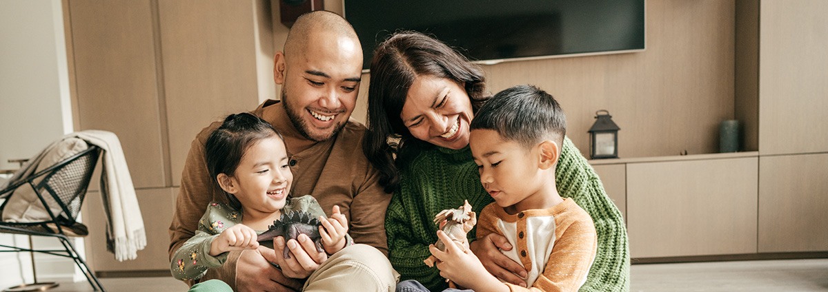 family of 4 sitting in livingroom little boy is holding a dinosaur